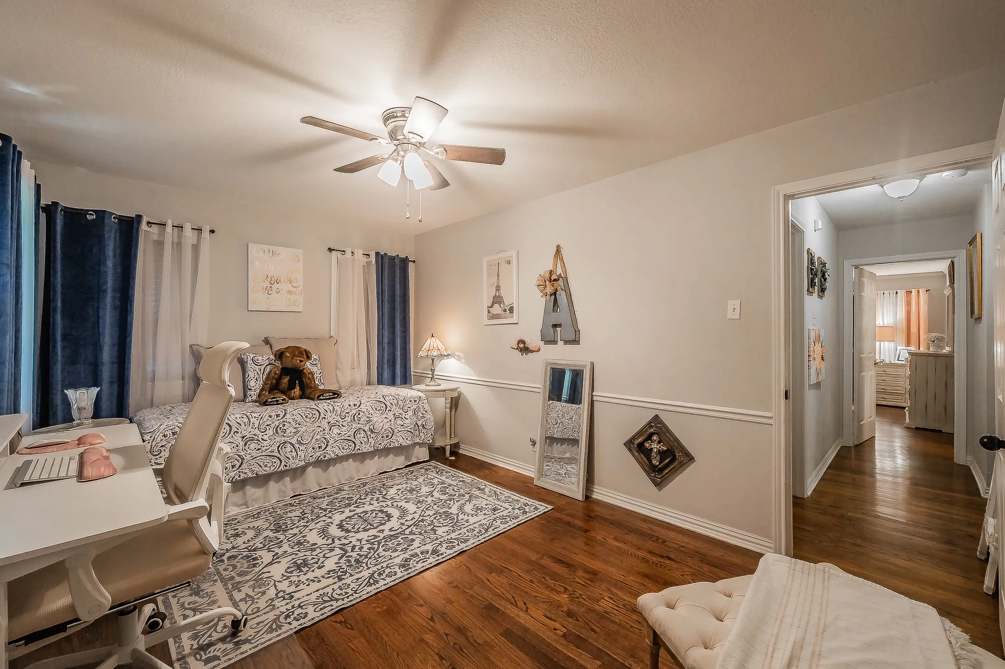 Hardwood flooring extends throughout this room, featuring a white chair rail molding, ceiling fan, and recessed lighting