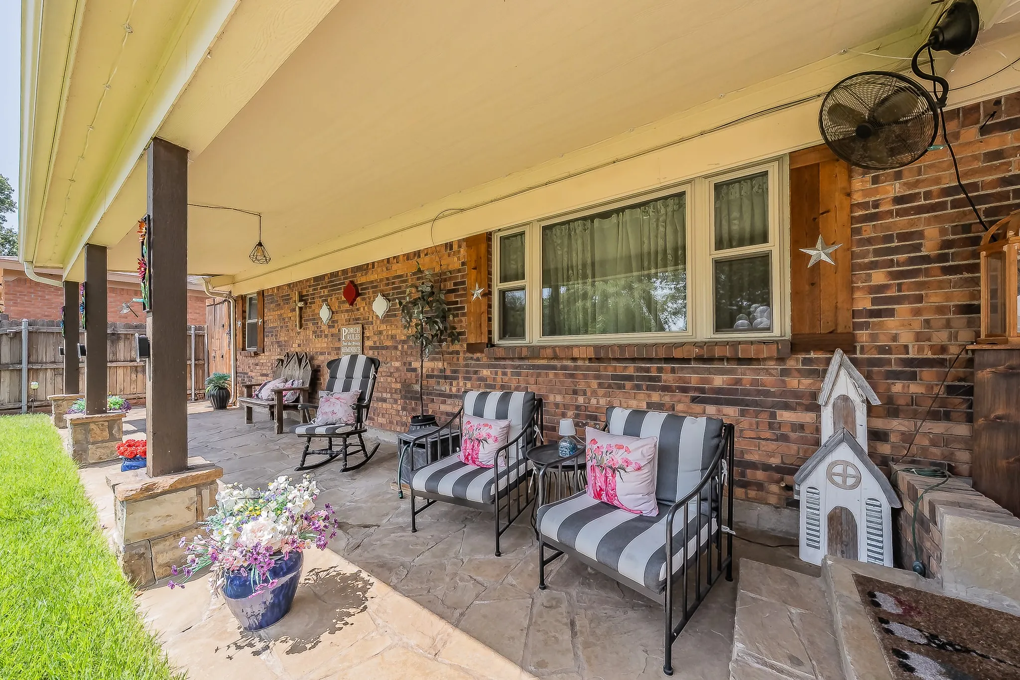 Covered patio featuring a stamped concrete surface, brick exterior wall, and multiple support columns with stone accents