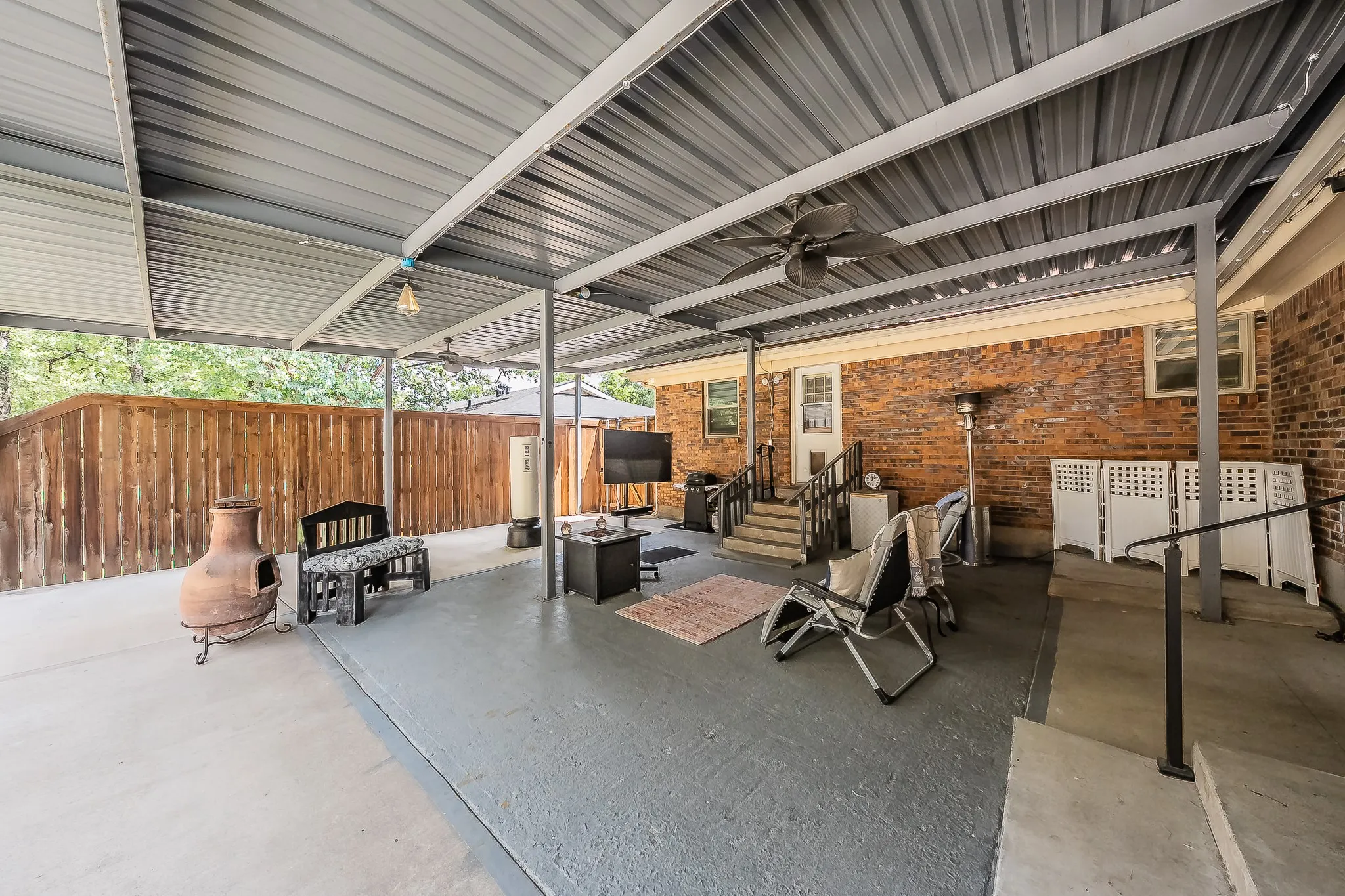 Expansive covered patio featuring a corrugated metal roof supported by metal beams