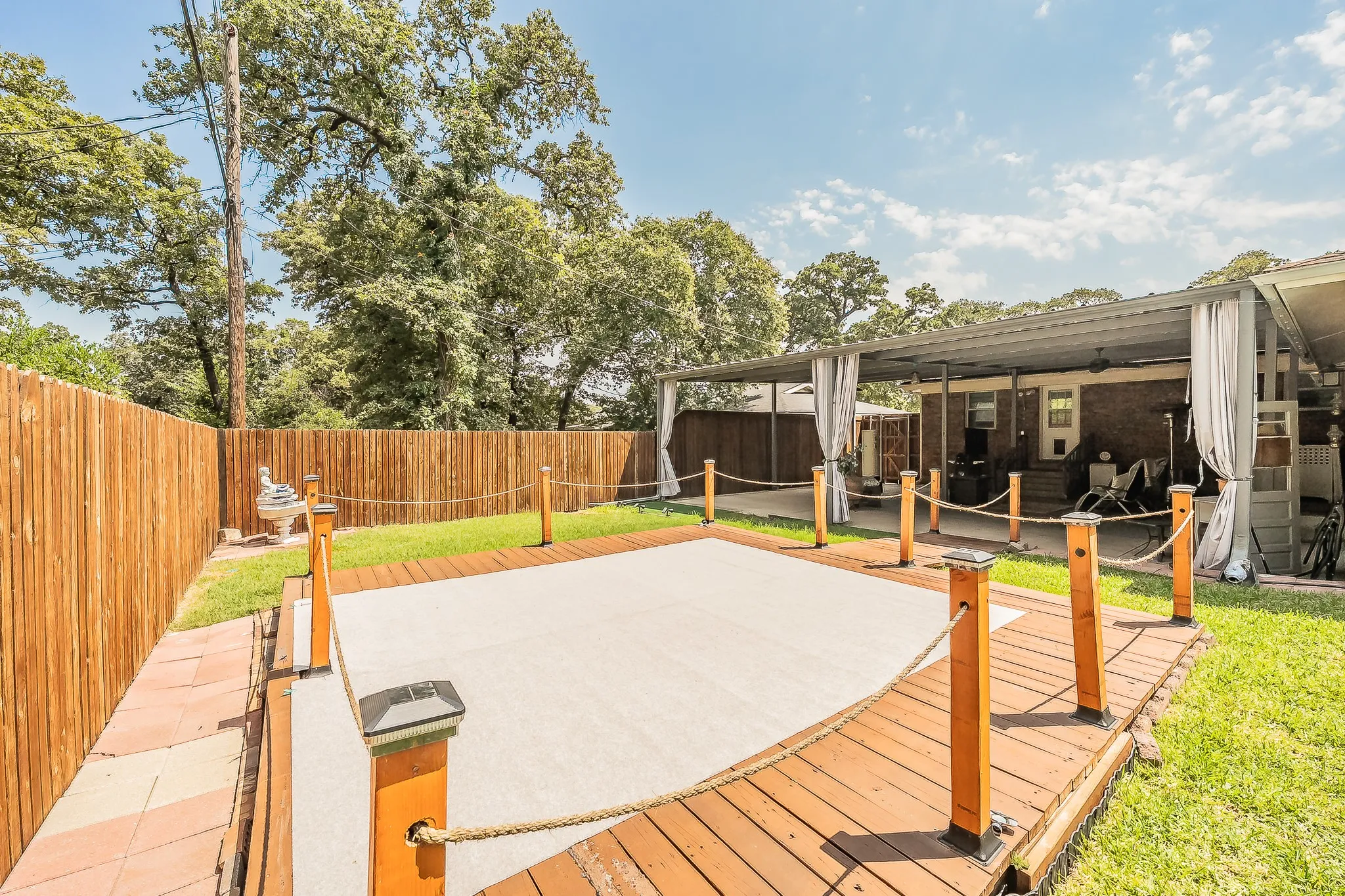 Expansive backyard featuring a covered patio, a wood privacy fence, and a pool deck with rope railings