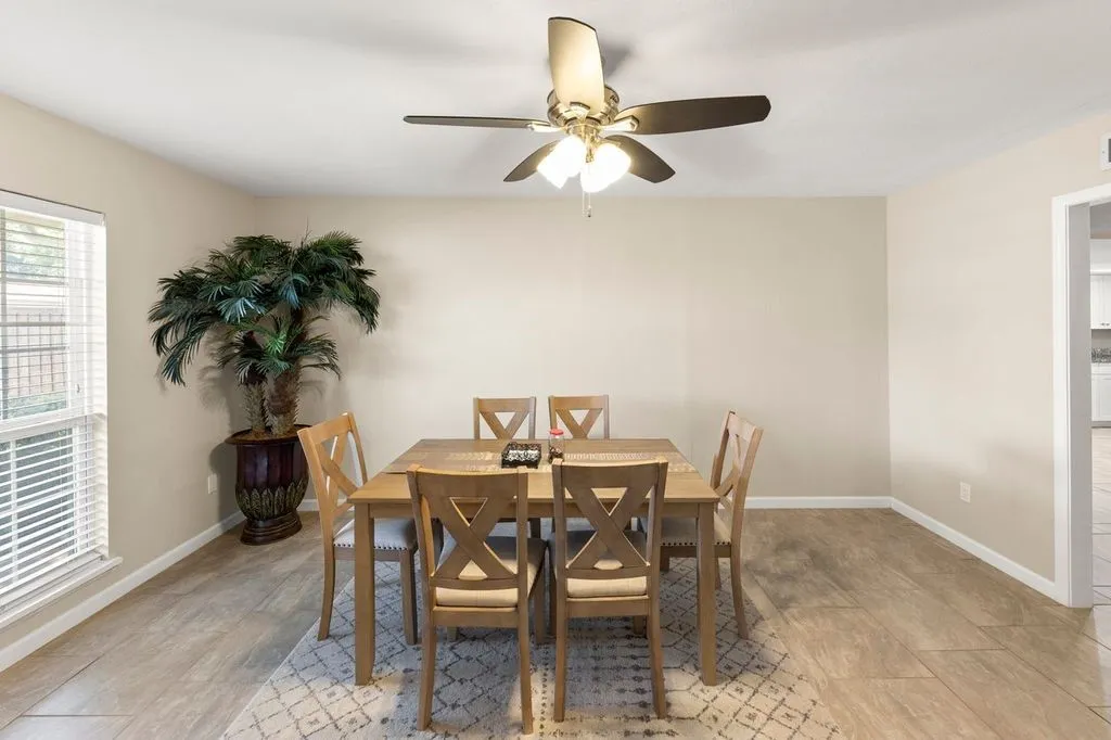 Dining area featuring neutral wall tones, wood-finish tile flooring, and a ceiling fan with integrated lighting