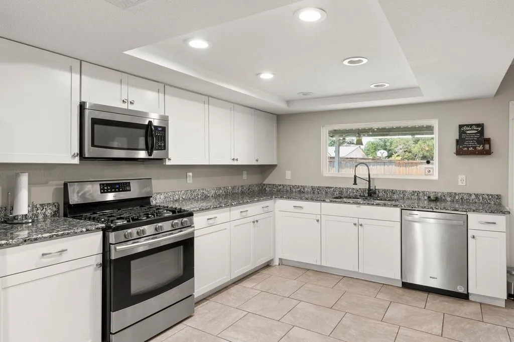 Kitchen featuring white cabinetry, granite countertops, stainless steel appliances, and recessed lighting