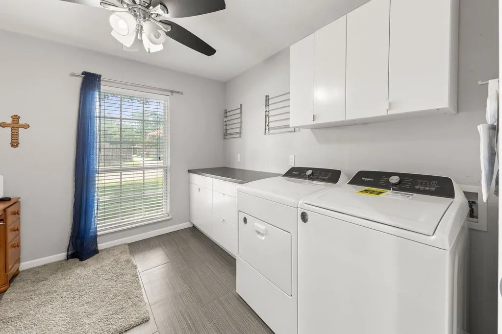 Dedicated laundry room featuring white cabinetry, a built-in countertop, and wood-finish flooring