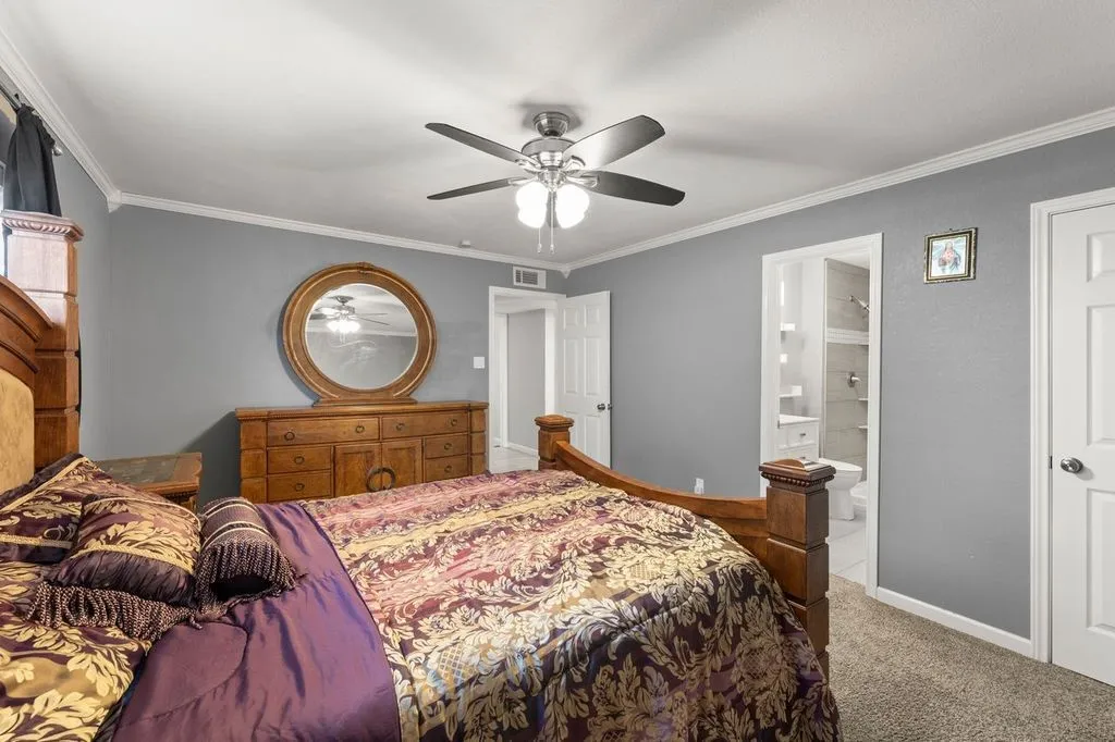Bedroom featuring grey walls, crown molding, a ceiling fan with integrated lighting, and carpeted flooring