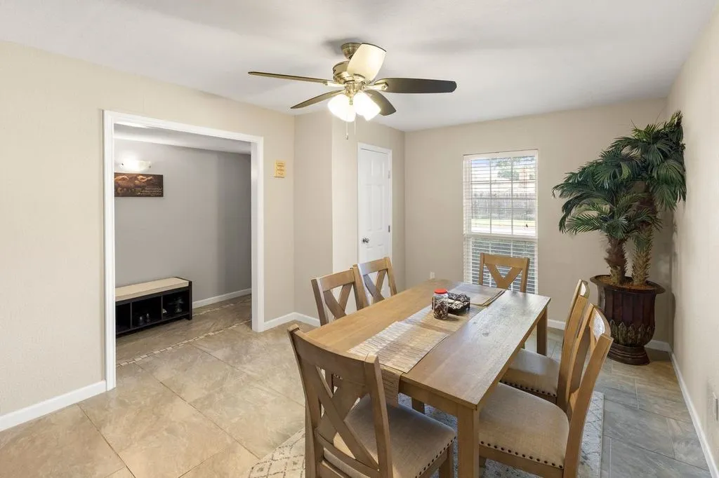 Dining area featuring neutral wall tones, tile flooring, a window with horizontal blinds, and a ceiling fan with integrated lighting