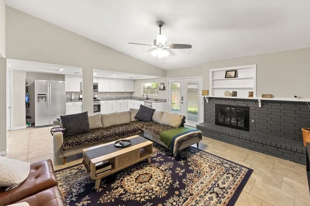Open-concept living space featuring vaulted ceilings, tile flooring, and a ceiling fan