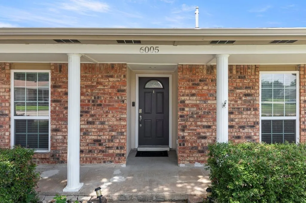 Brick exterior featuring a covered entry with two white​​‌​​​​‌​​‌‌​‌‌​​​‌‌​‌​‌​‌​​​‌​​ columns