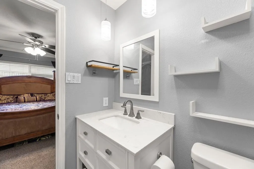 Bathroom featuring a white vanity with an integrated sink, a light-toned countertop, and a framed mirror