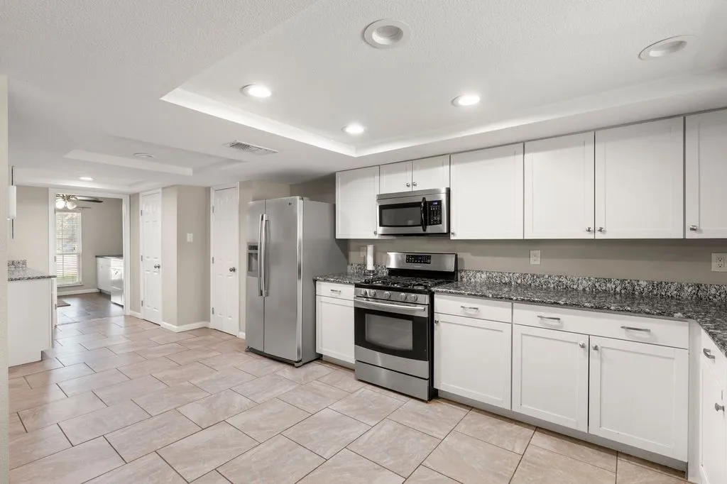 Kitchen featuring extensive white cabinetry, stainless steel appliances, granite countertops, and recessed lighting