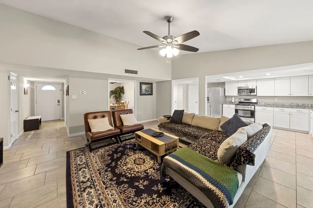 Open-concept living space featuring vaulted ceilings, tile flooring, and a ceiling fan with integrated lighting