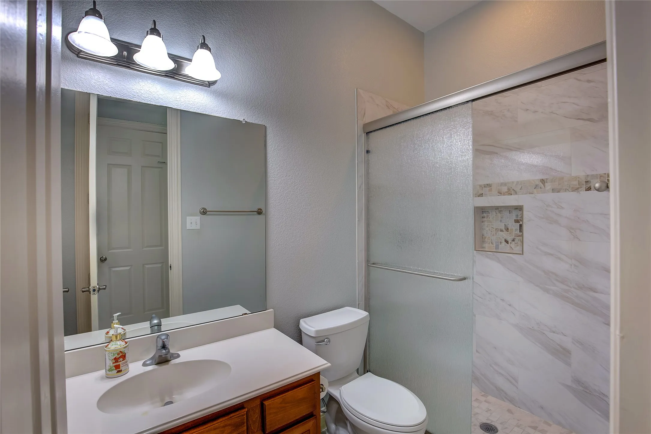 Bathroom featuring vanity, walk in shower, and toilet