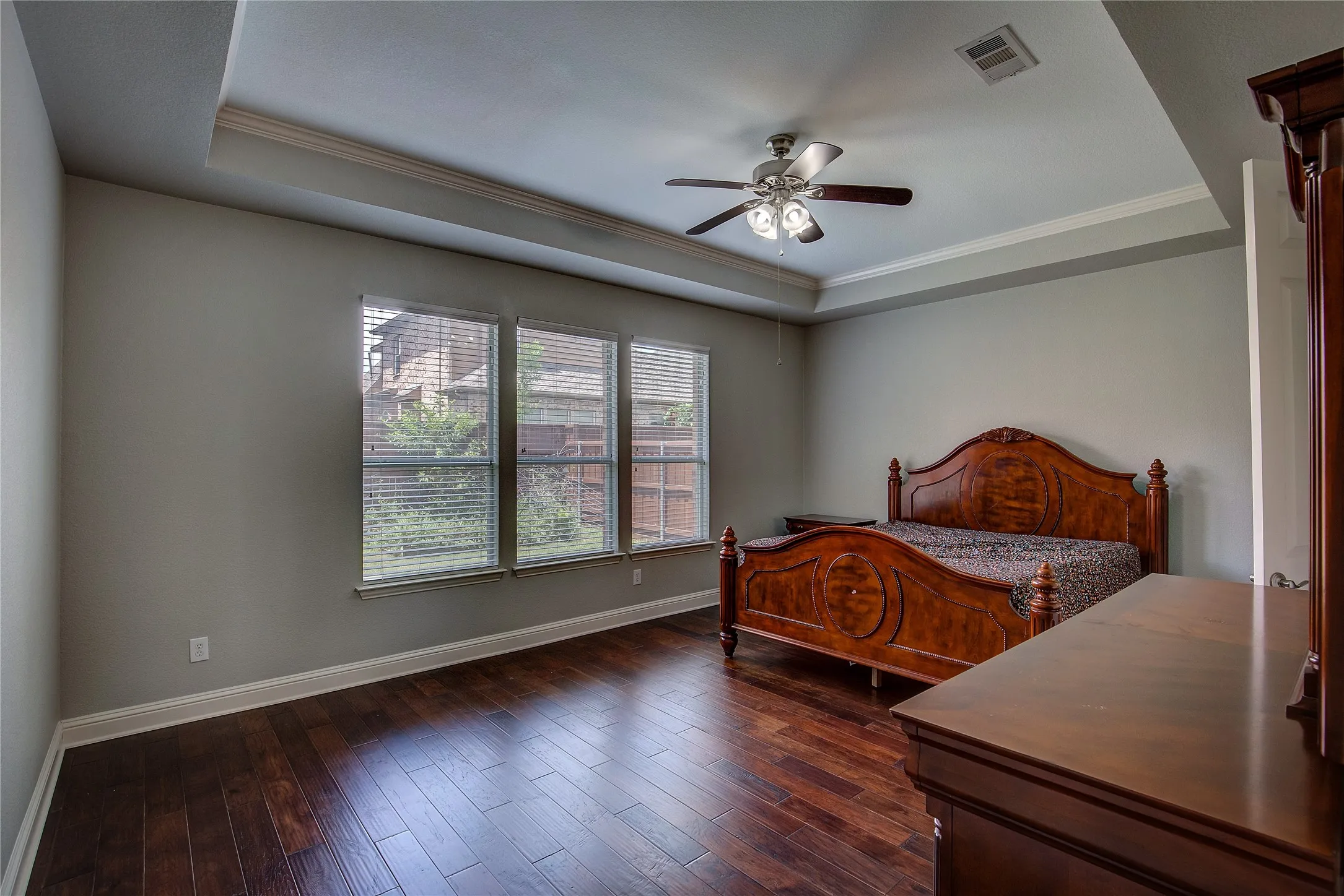 Bedroom featuring a raised ceiling, ceiling fan, dark hardwood / wood-style floors, and crown molding