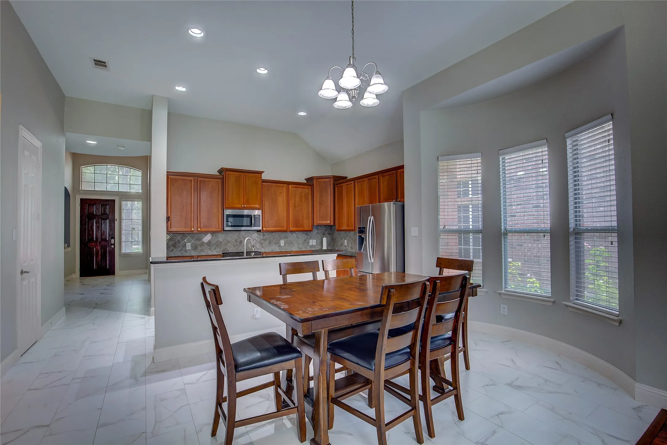 Dining room featuring a chandelier, lofted ceiling, and light tile patterned floors