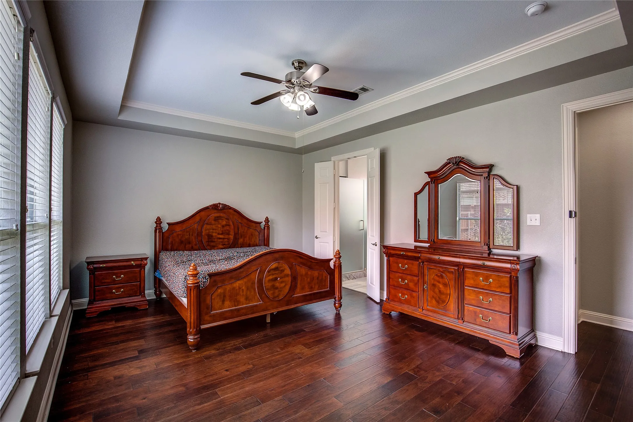 Bedroom with crown molding, ceiling fan, dark hardwood / wood-style floors, and a tray ceiling