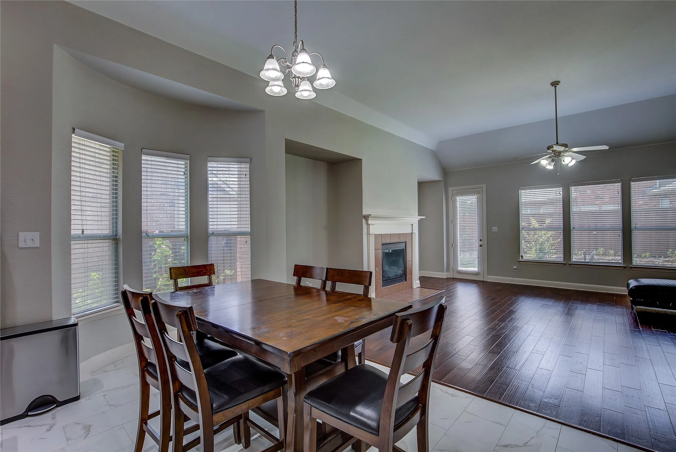 Dining area featuring a fireplace, ceiling fan with notable chandelier, light hardwood / wood-style flooring, and plenty of natural light