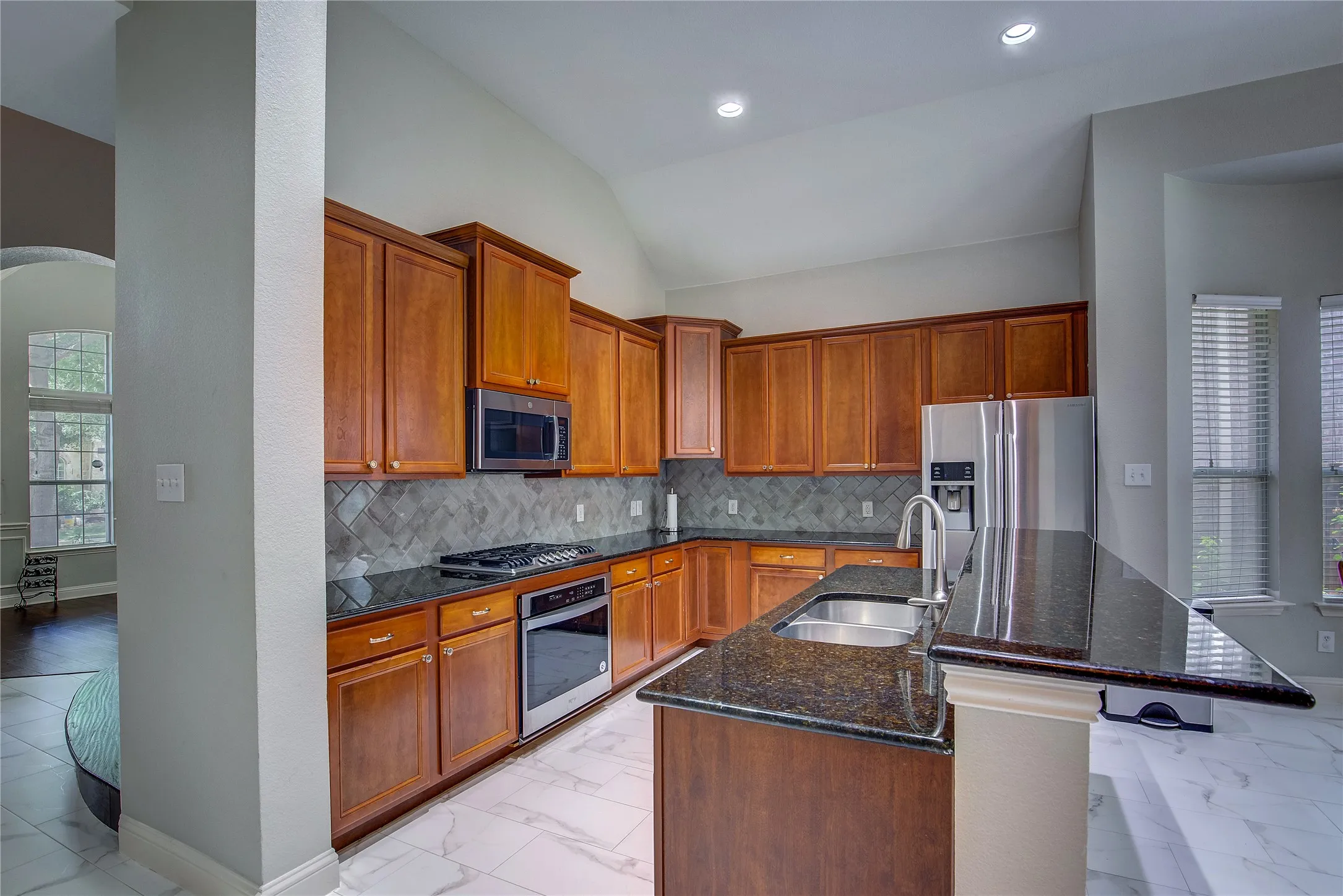 Kitchen with light tile patterned flooring, decorative backsplash, appliances with stainless steel finishes, and sink