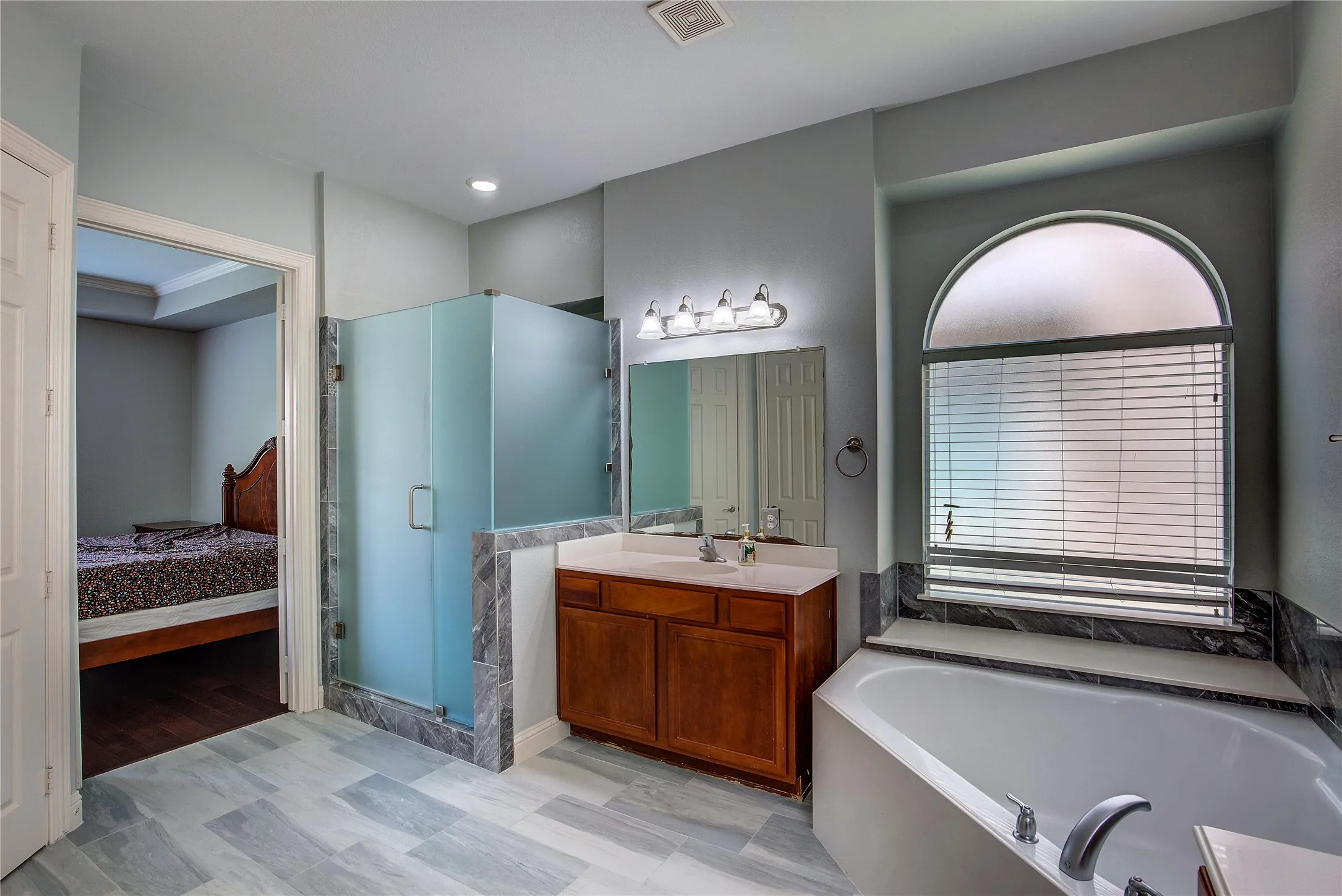 Bathroom featuring vanity, plus walk in shower, crown molding, and wood-type flooring