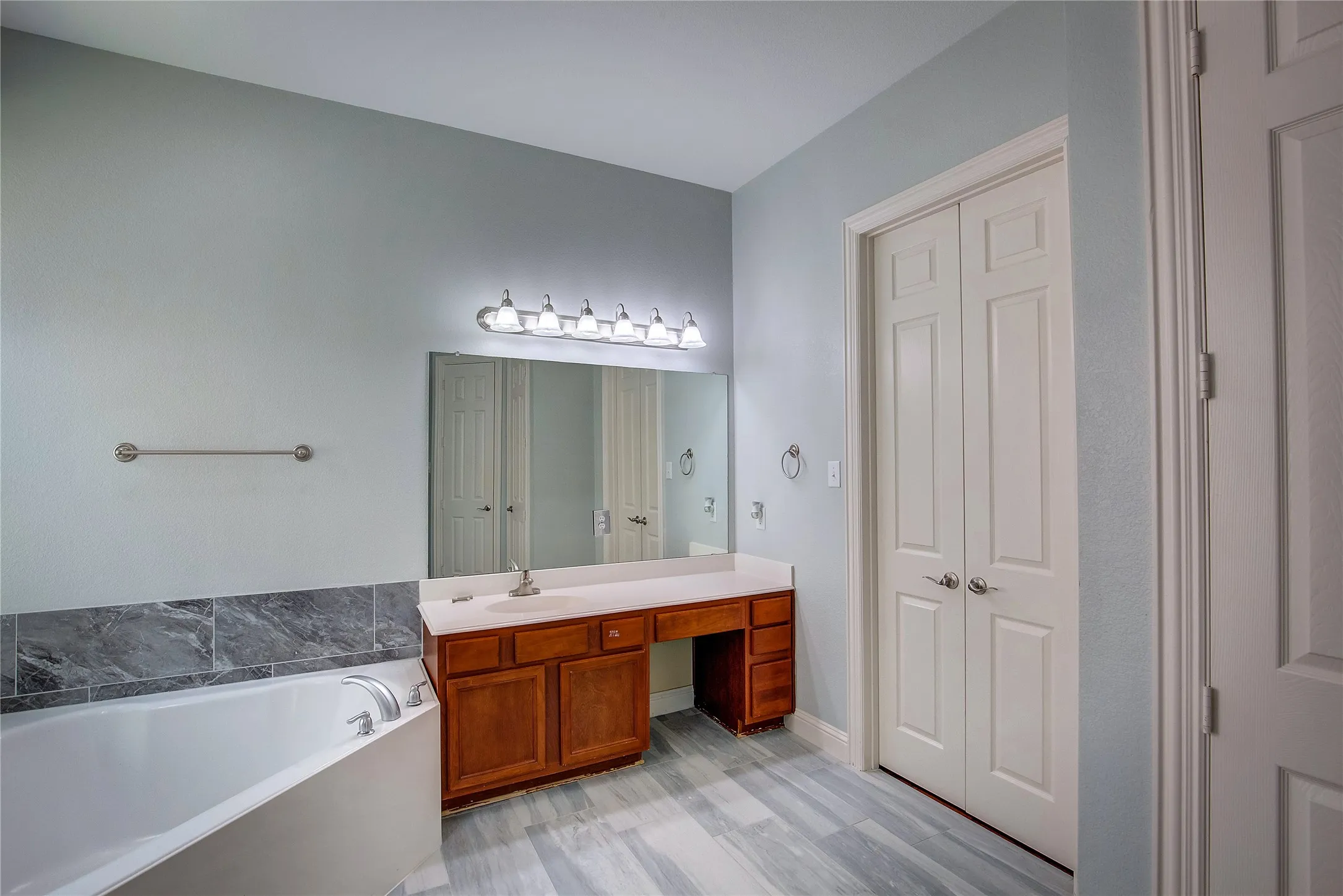 Bathroom featuring wood-type flooring, a bathing tub, and vanity
