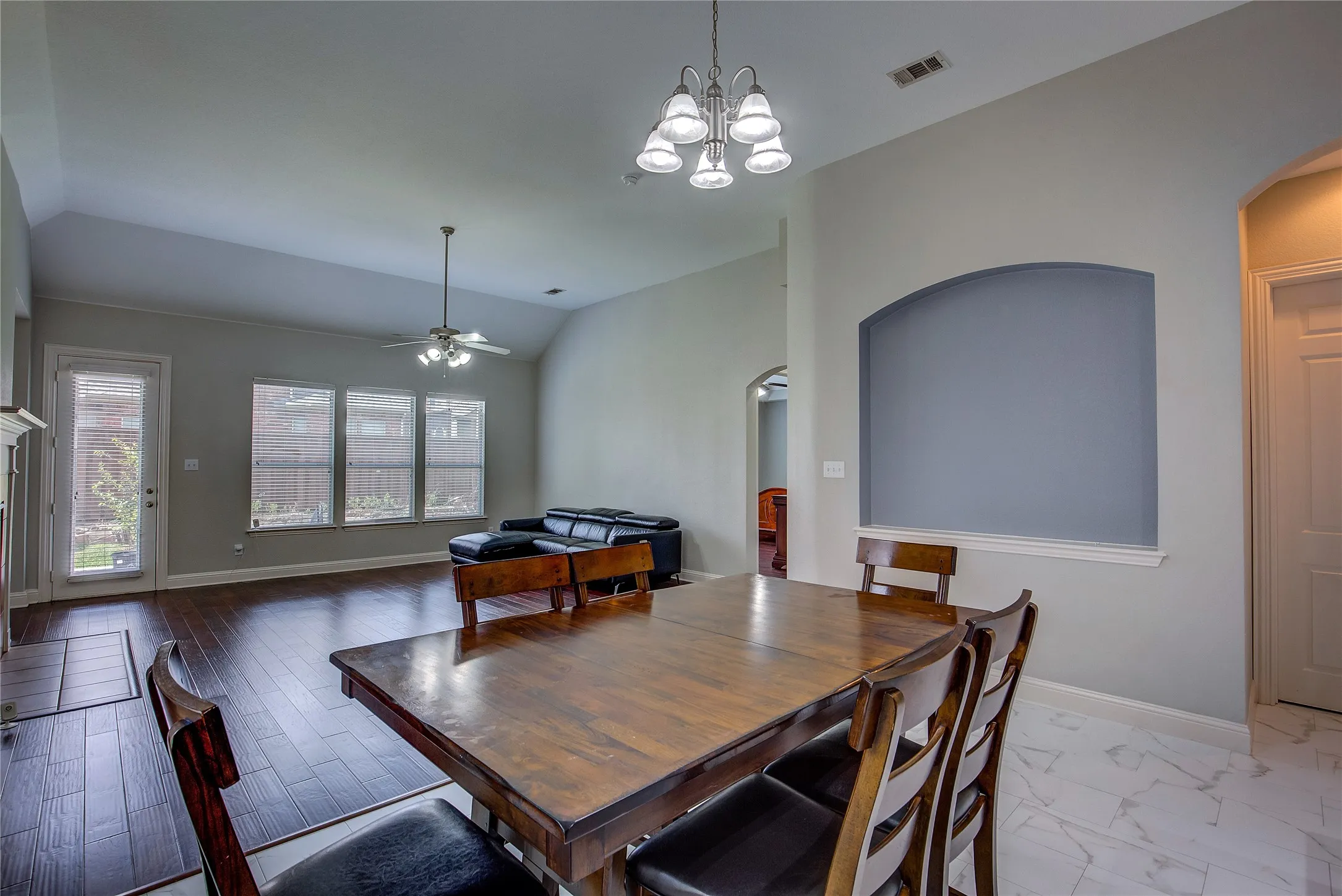 Dining room with lofted ceiling, light hardwood / wood-style floors, and ceiling fan with notable chandelier