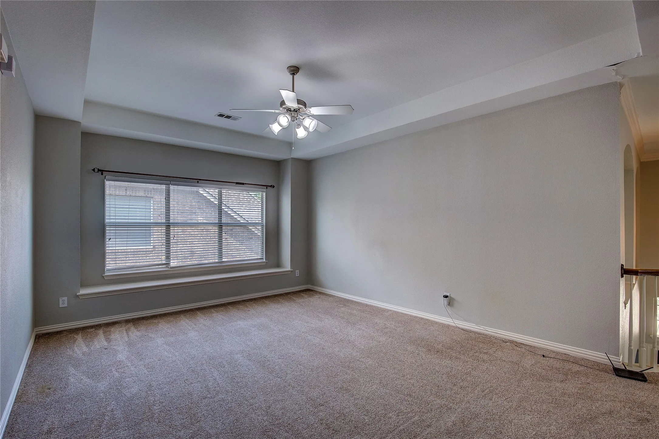 Carpeted empty room featuring ceiling fan and a raised ceiling