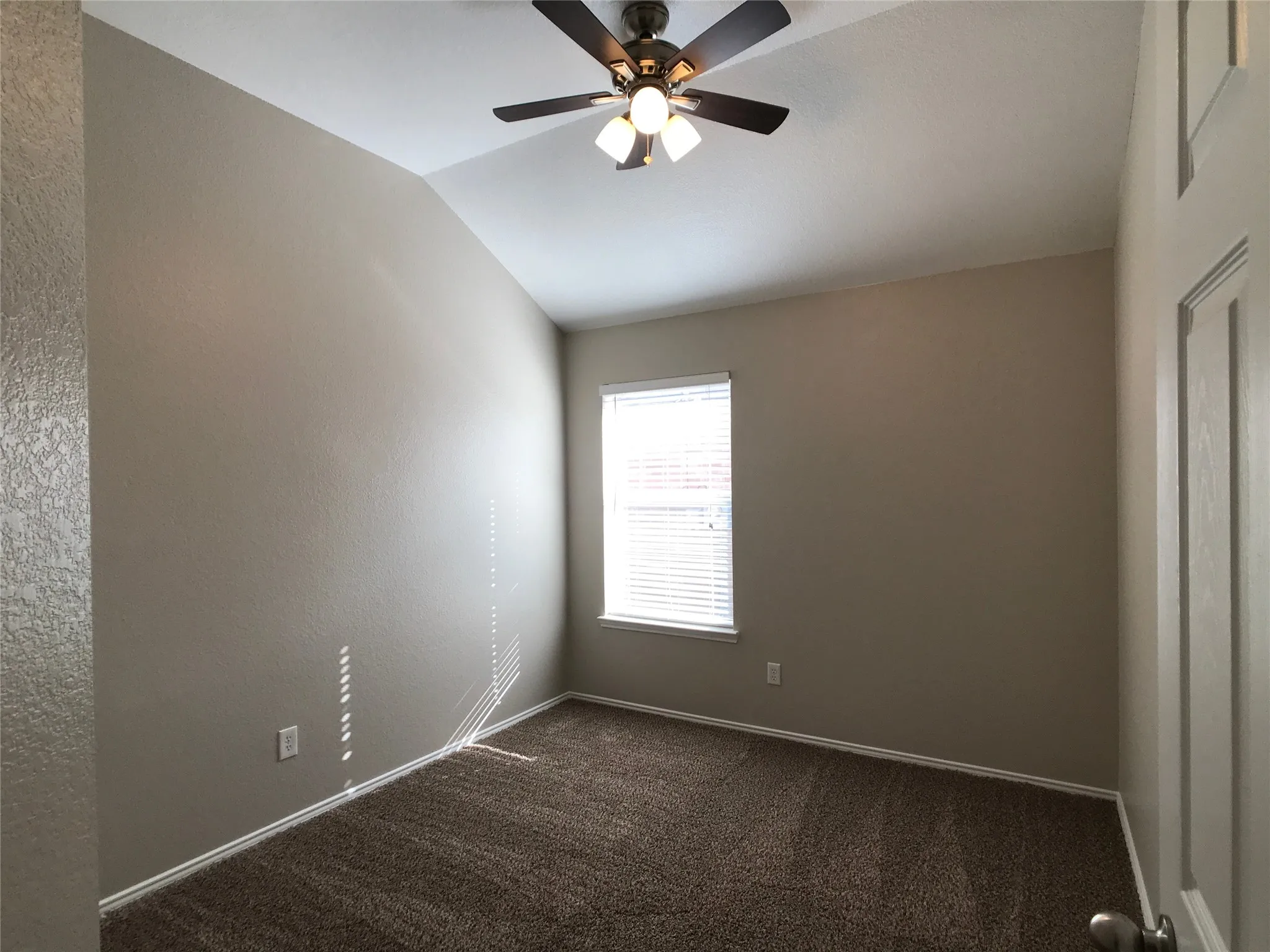 Interior room featuring vaulted ceilings and a ceiling fan with integrated lighting