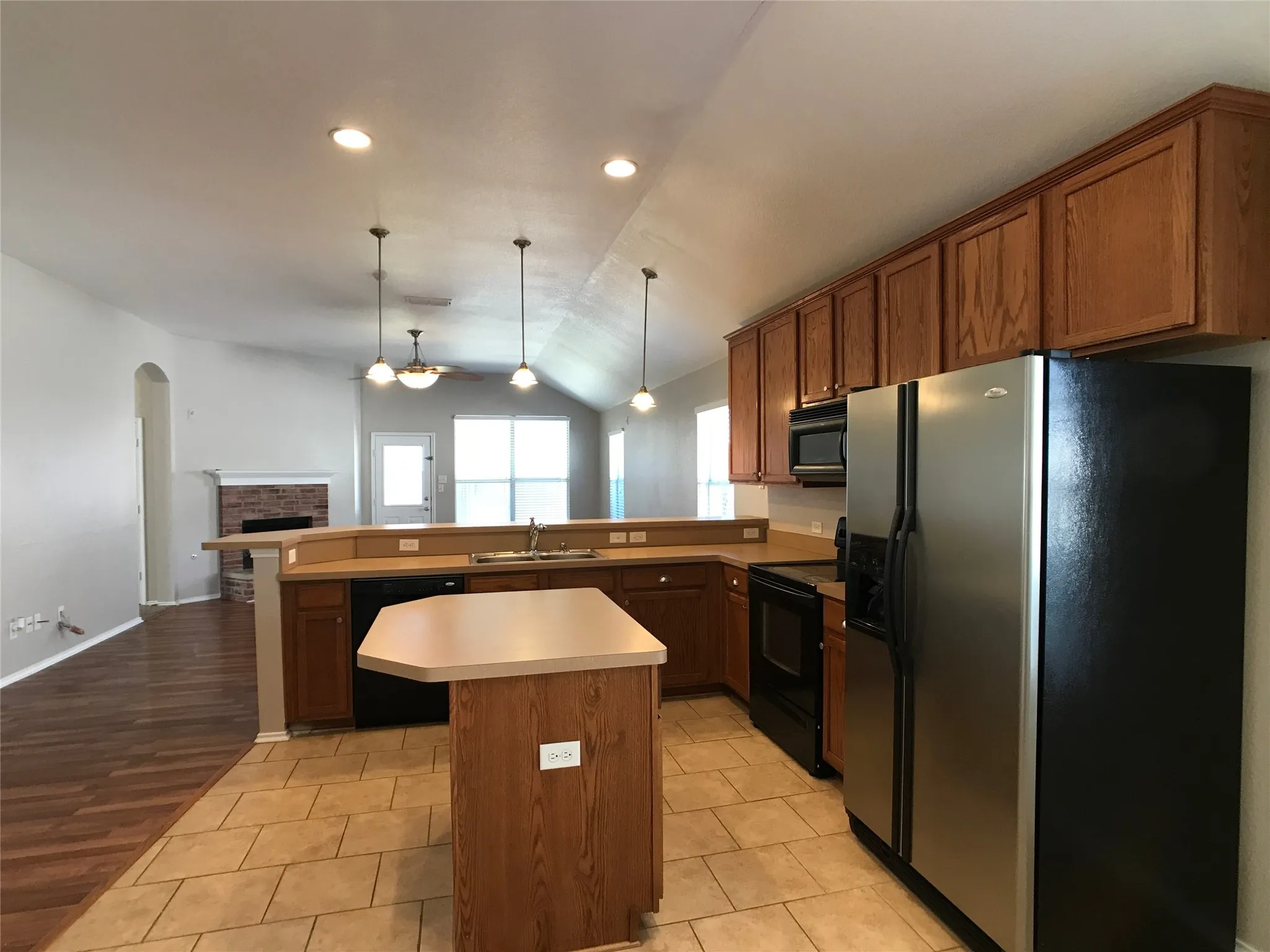 Kitchen featuring stainless steel appliances, wood-finish cabinetry, a built-in island, and tile flooring