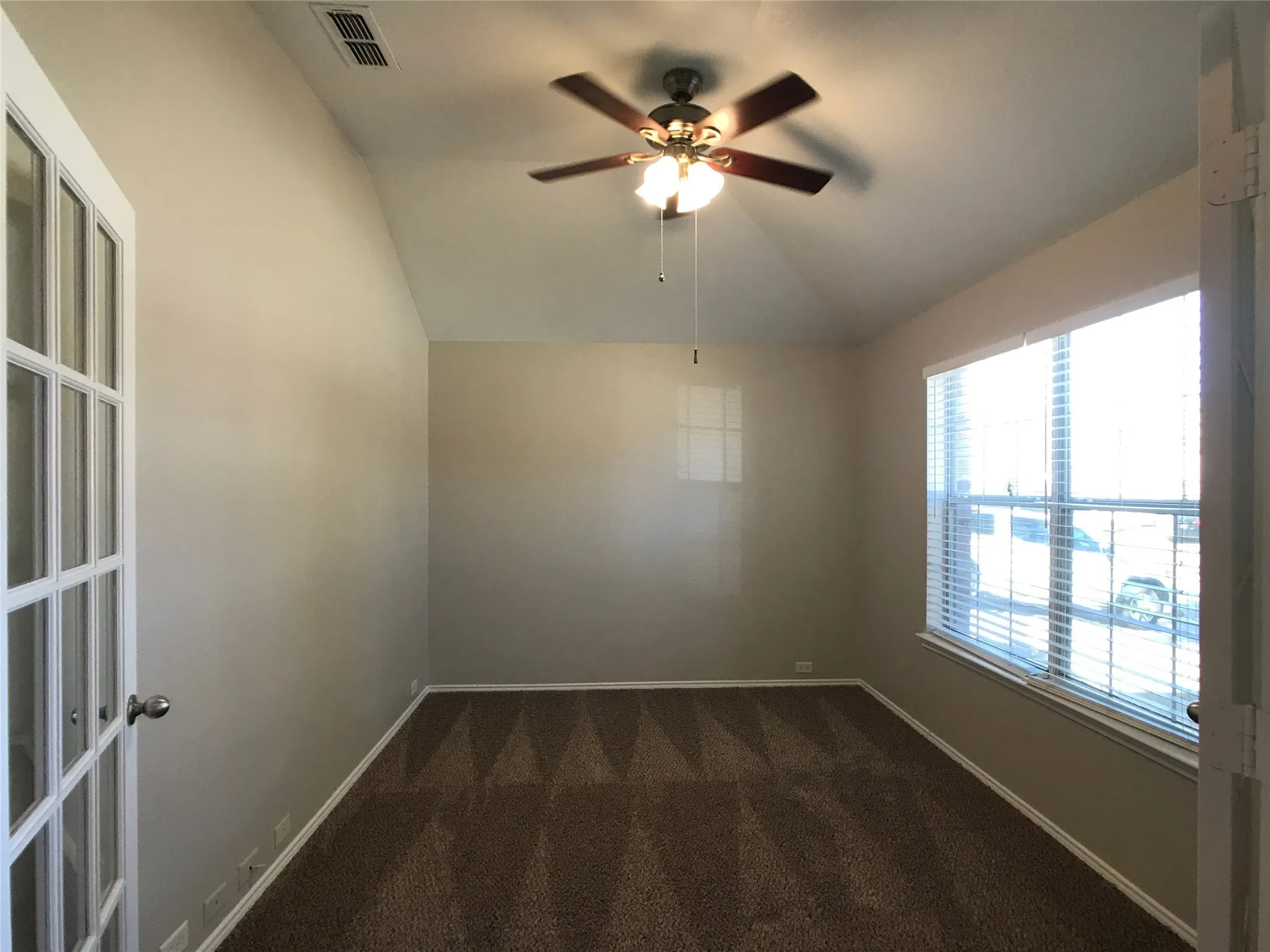 Room featuring a vaulted ceiling and a ceiling fan with integrated lighting