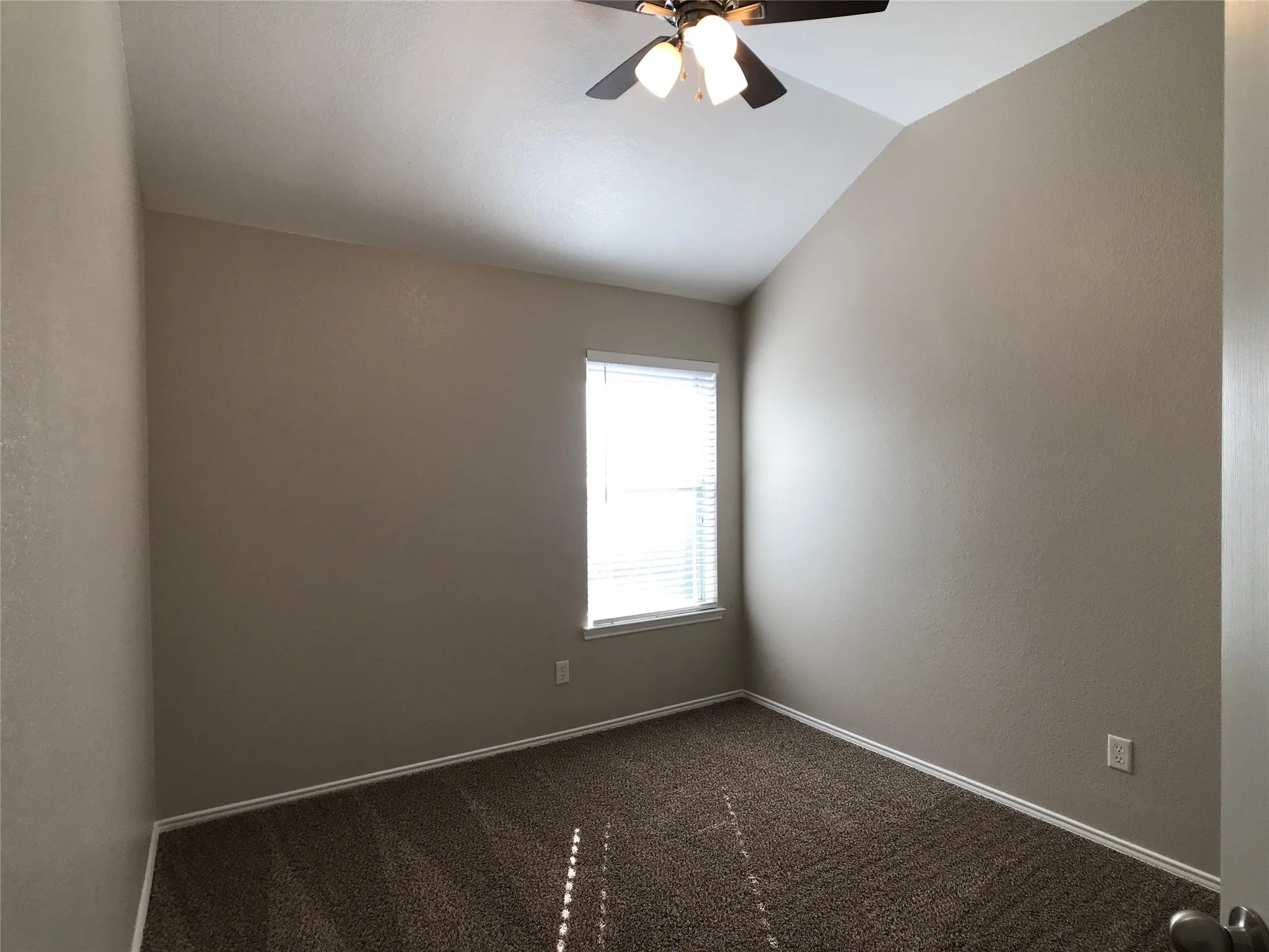 Bedroom featuring neutral wall color, vaulted ceiling, and a ceiling fan with integrated lighting