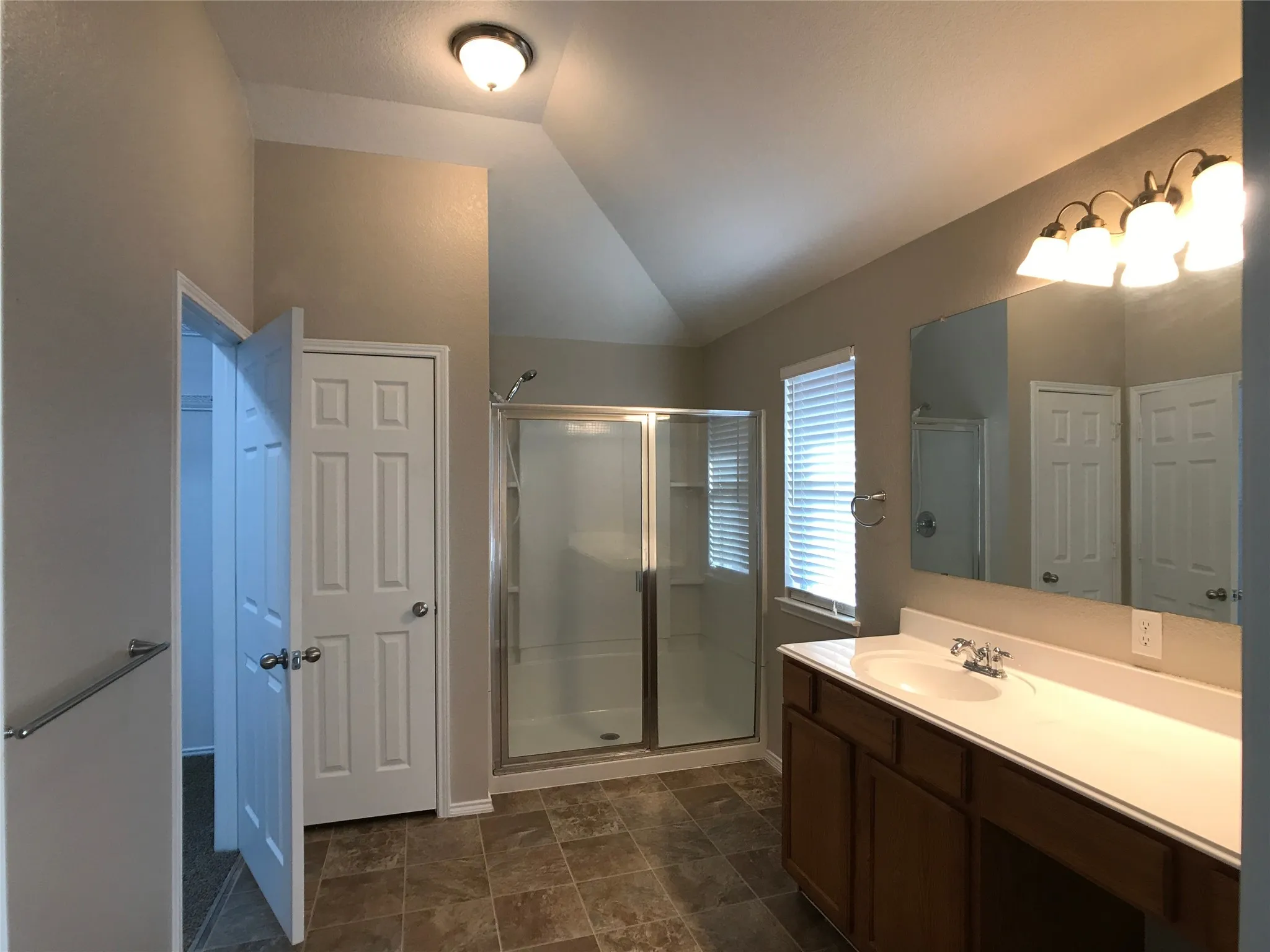Bathroom featuring a glass-enclosed shower, a vanity with an integrated sink and white countertop, wood-finish cabinetry, and tiled flooring