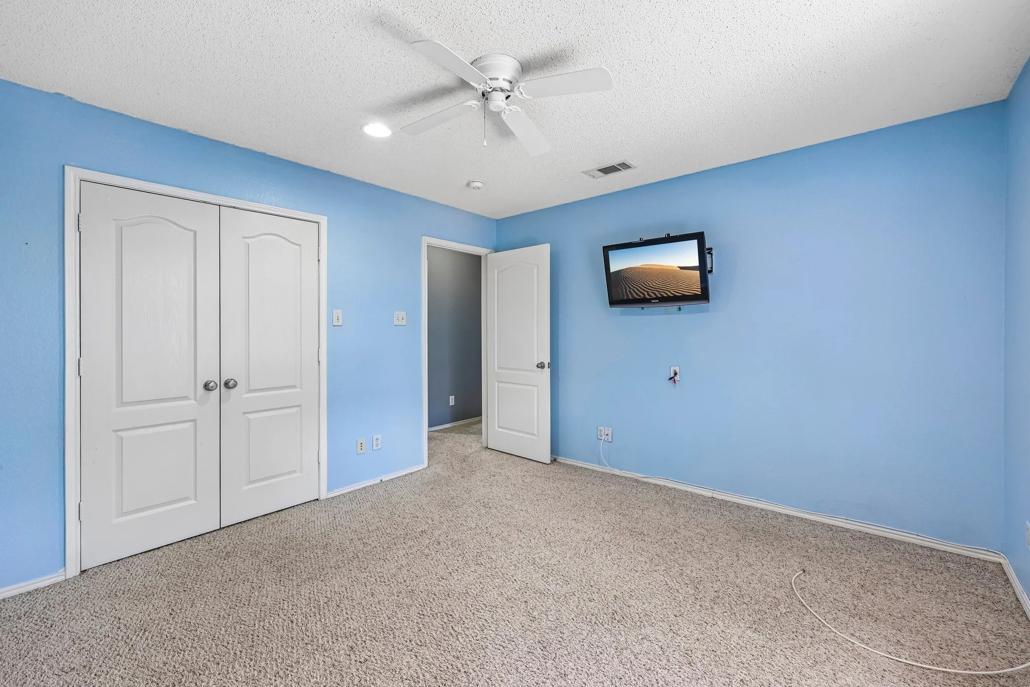 Room featuring light blue walls, a textured ceiling, and carpeting