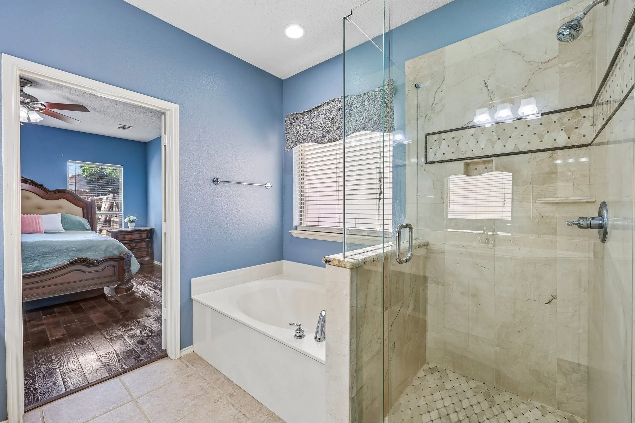 Bathroom featuring a glass-enclosed shower with tile surround, a built-in tub, and tile flooring