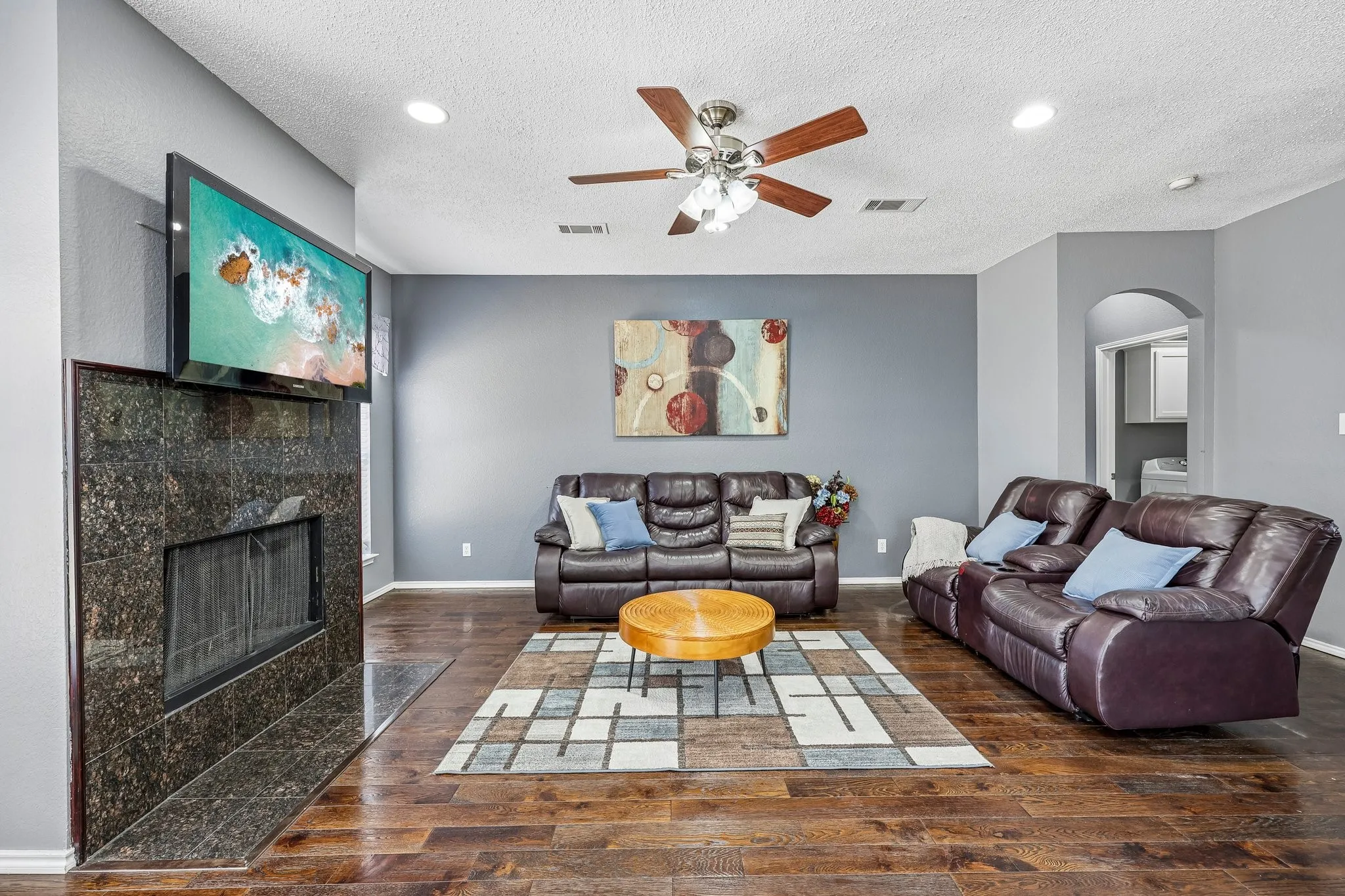 Living area featuring wood-finish flooring and a stone-clad fireplace