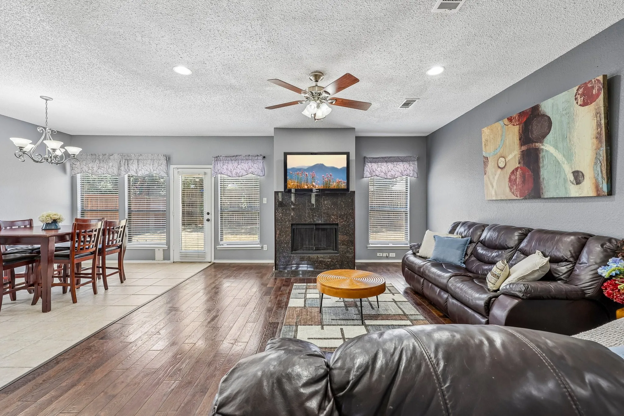 Spacious living area featuring wood-finish flooring, a contemporary ceiling fan, and recessed lighting