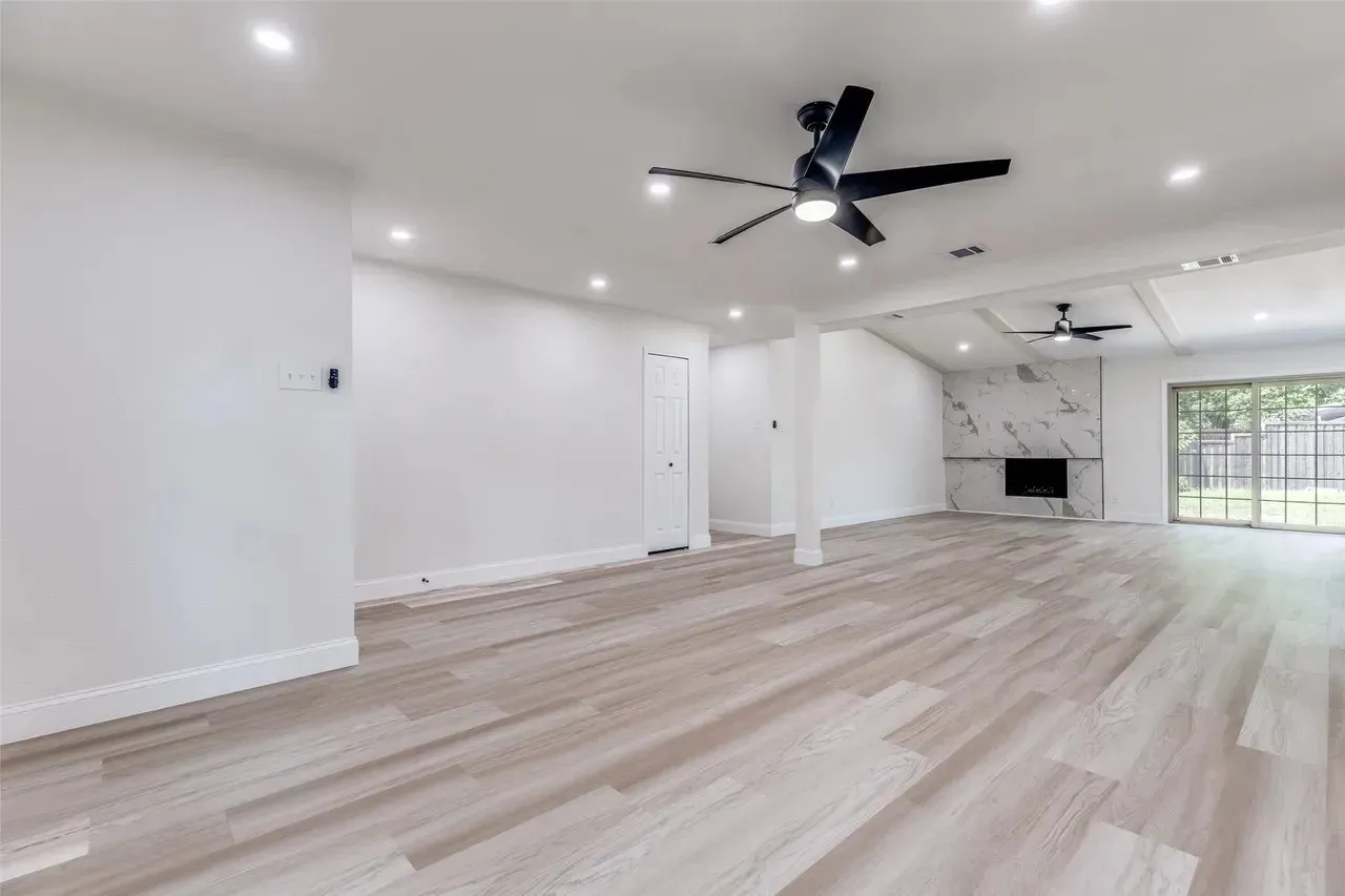 Spacious open-concept living area featuring wide-plank wood-finish flooring, recessed ceiling lighting, and a modern ceiling fan with integrated light fixture
