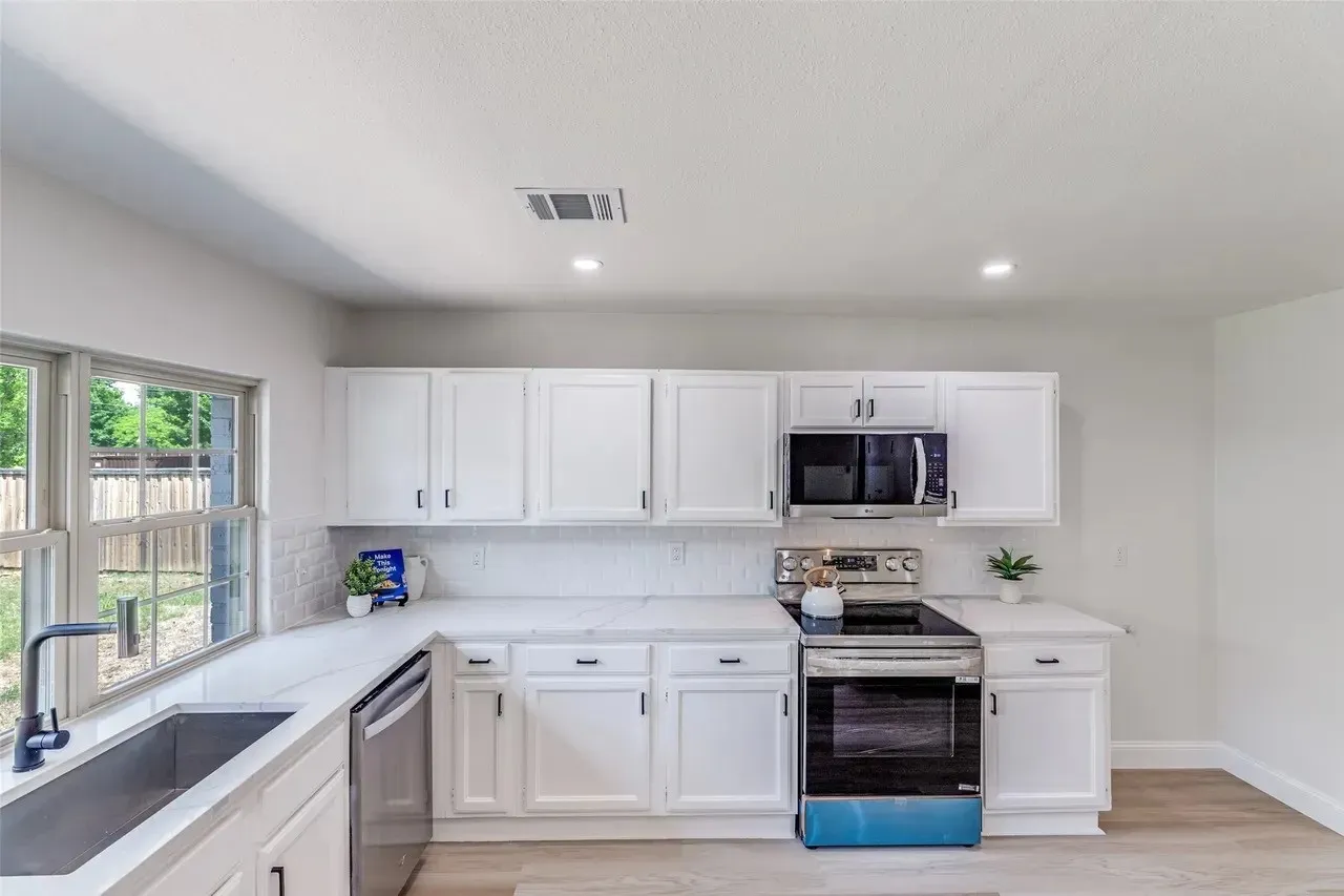 Modern kitchen featuring white cabinetry, light countertops, subway tile backsplash, and stainless steel appliances