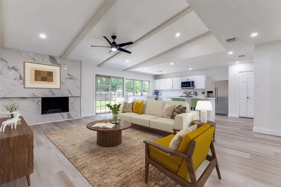 Spacious living area featuring a vaulted ceiling with exposed beams, recessed lighting, and wood-finish flooring