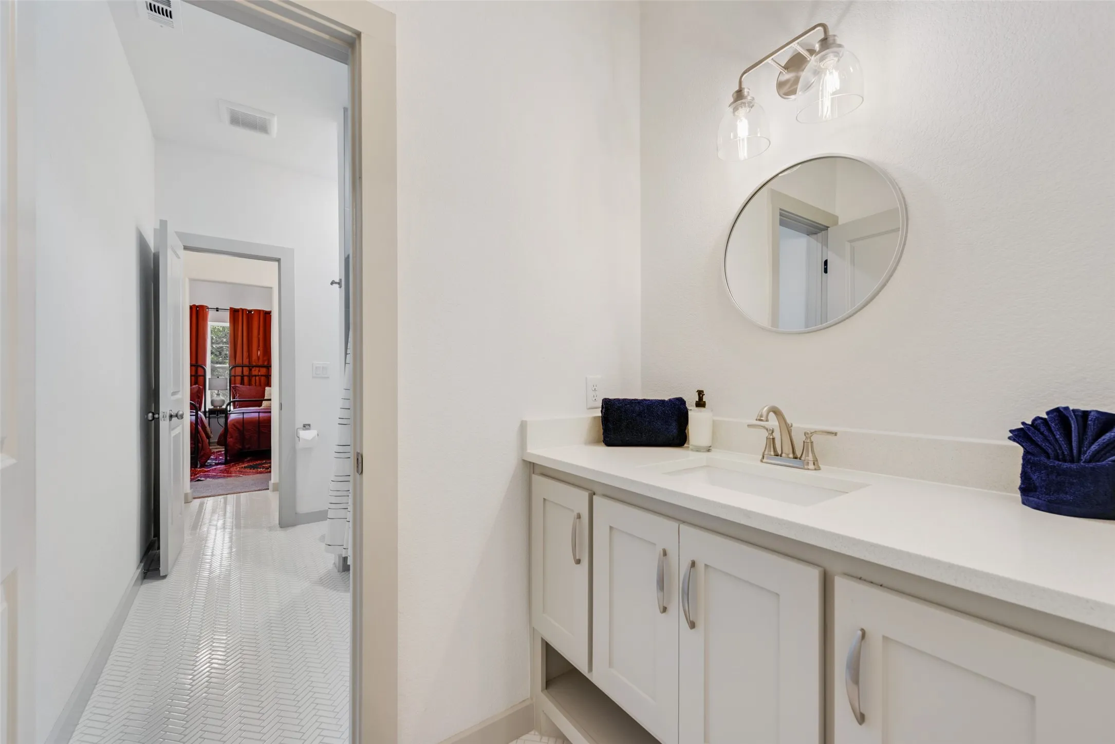 Bathroom vanity featuring a light-toned countertop with an integrated sink and brushed nickel faucet