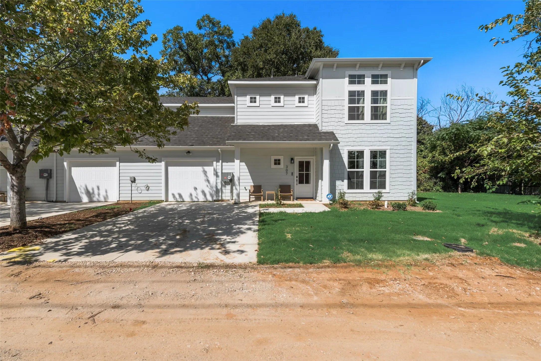 Modern two-story home featuring white fiber cement siding, multi-pane windows, and a pitched roof with architectural detailing