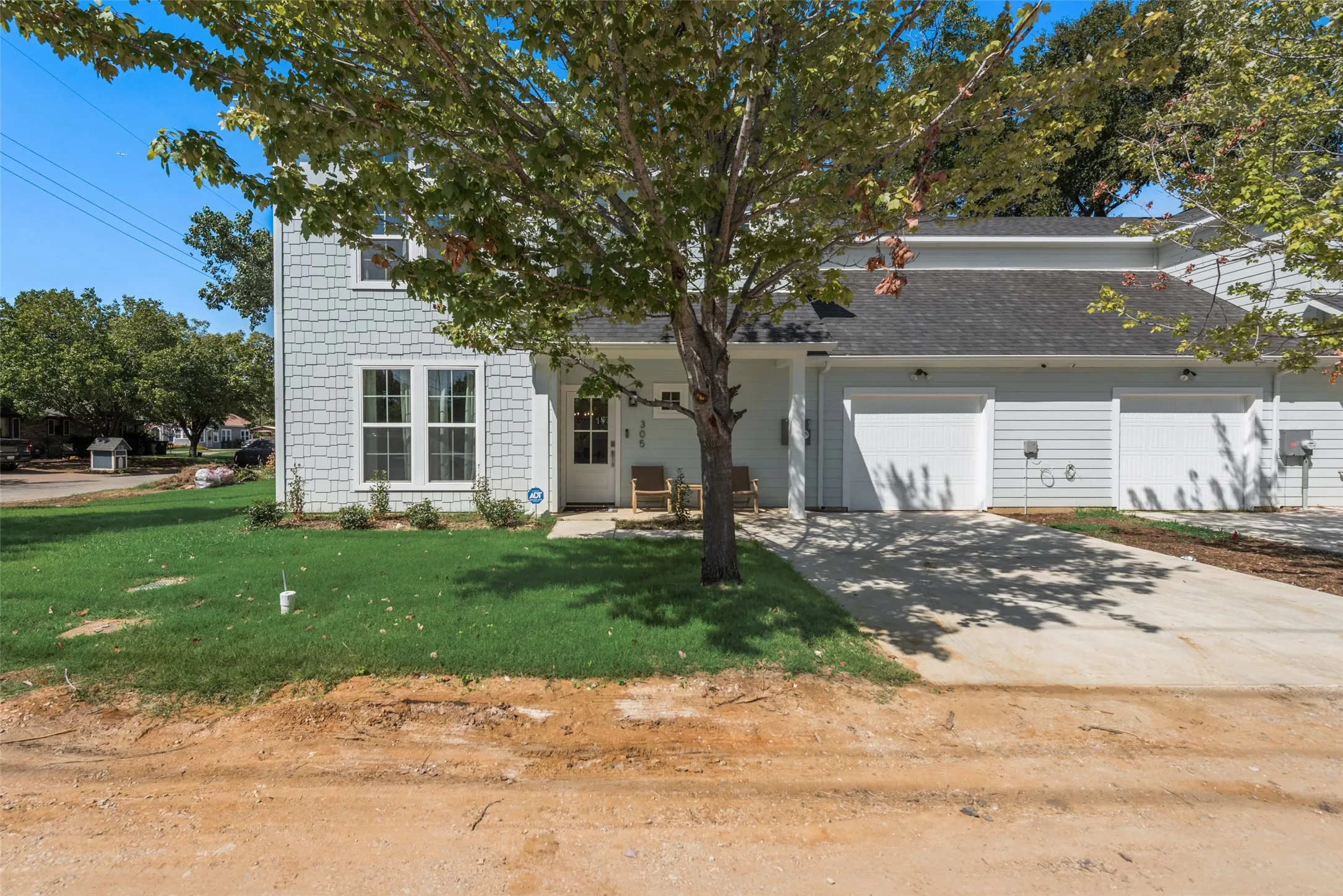 Contemporary white-exterior home featuring a classic pitched-roof design with attached two-car garage