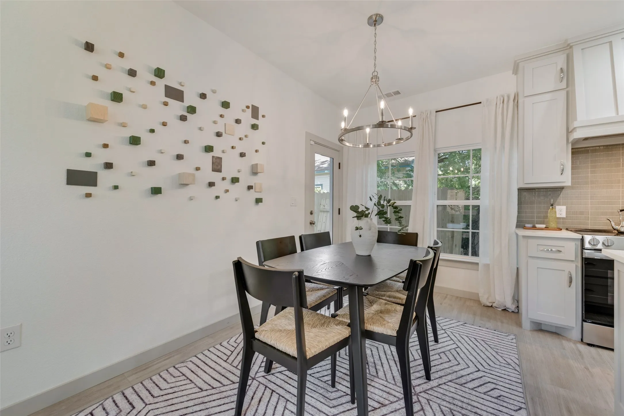 Bright dining area featuring a wood-finish table with seating for four, pendant lighting fixture, and direct access to the kitchen