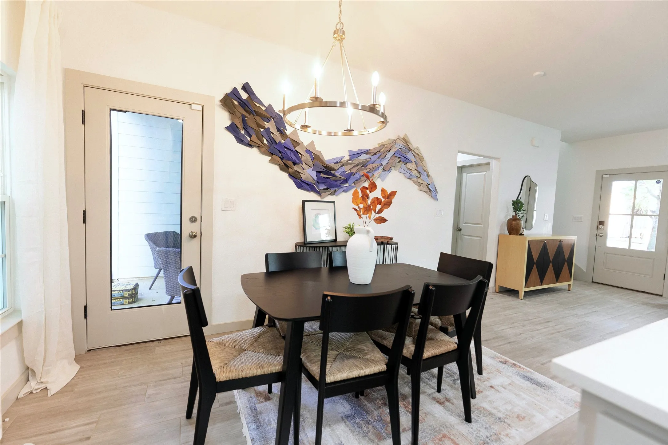 Elegant dining area showcasing a round wood-finish table paired with black upholstered chairs, anchored by a contemporary pendant light fixture