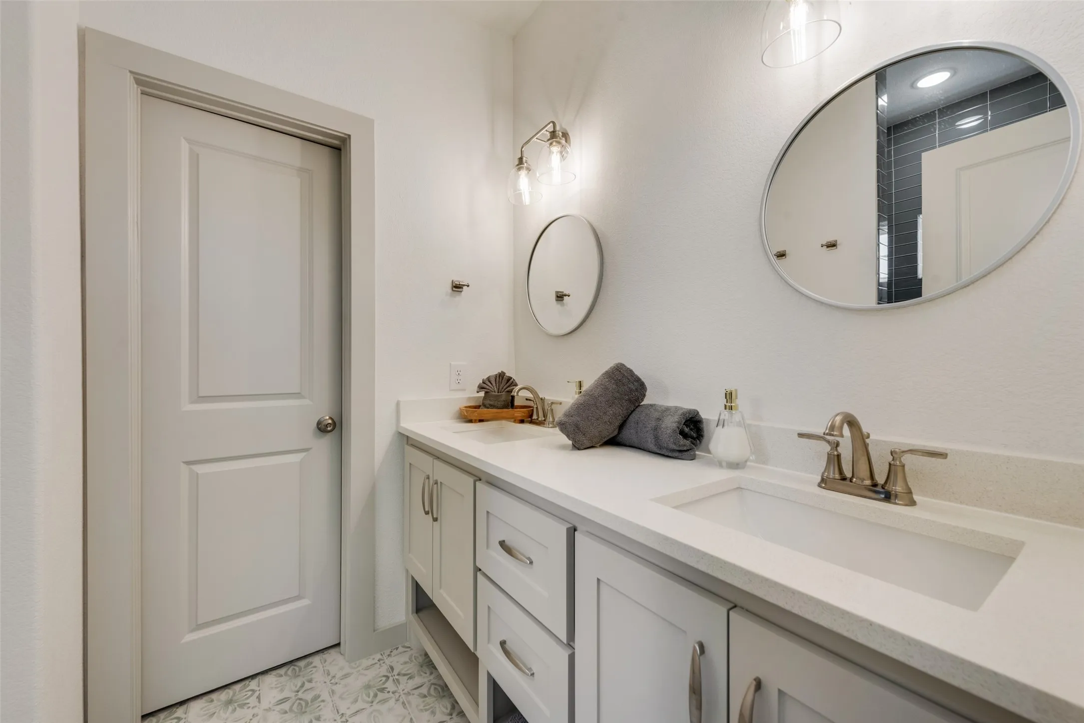 Spa-inspired primary bathroom showcasing a white shaker-style vanity with dual drawers, white quartz countertop, and brushed nickel widespread faucet
