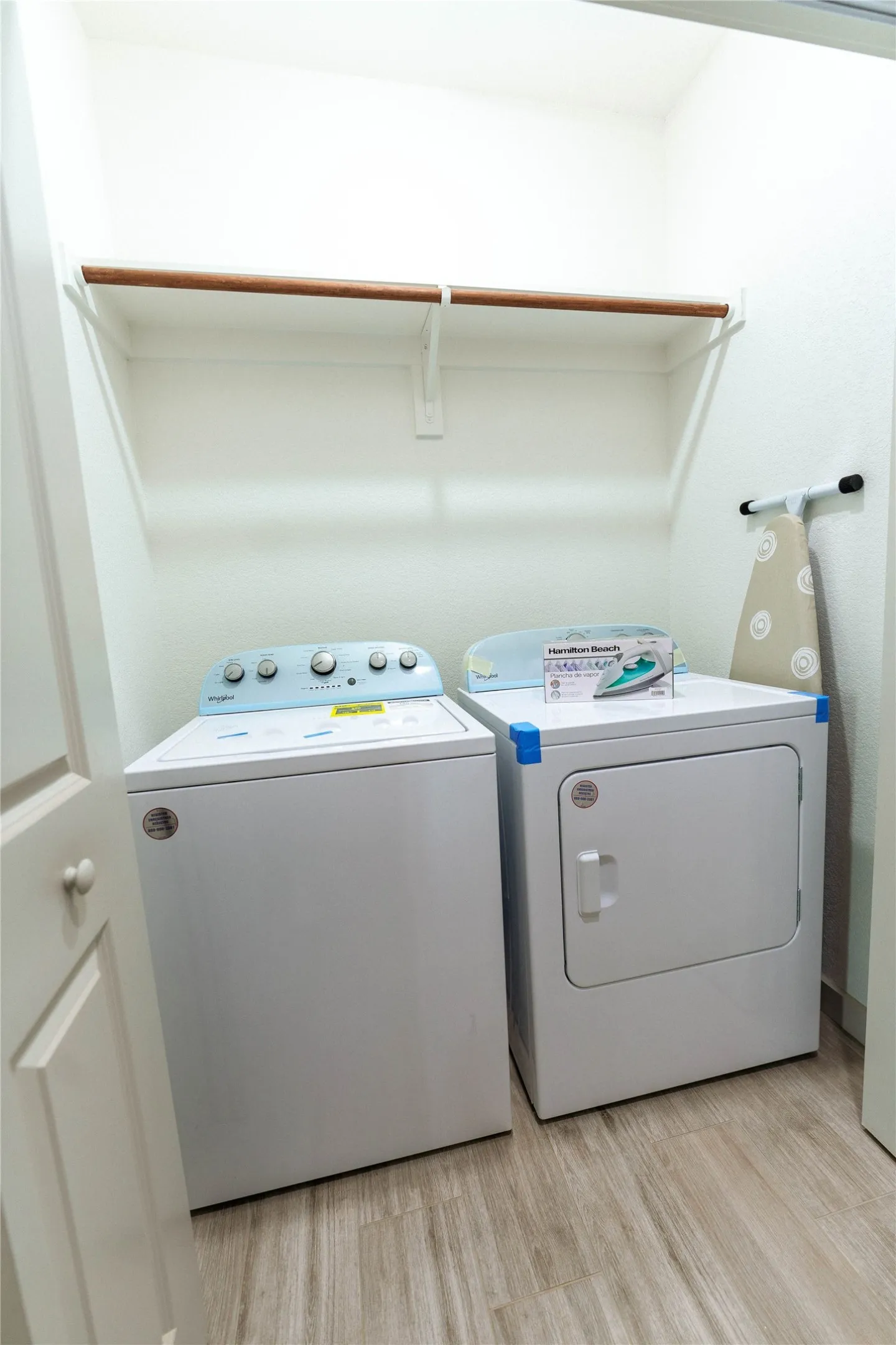 Laundry area featuring wood-finish flooring and a built-in hanging rod with shelving