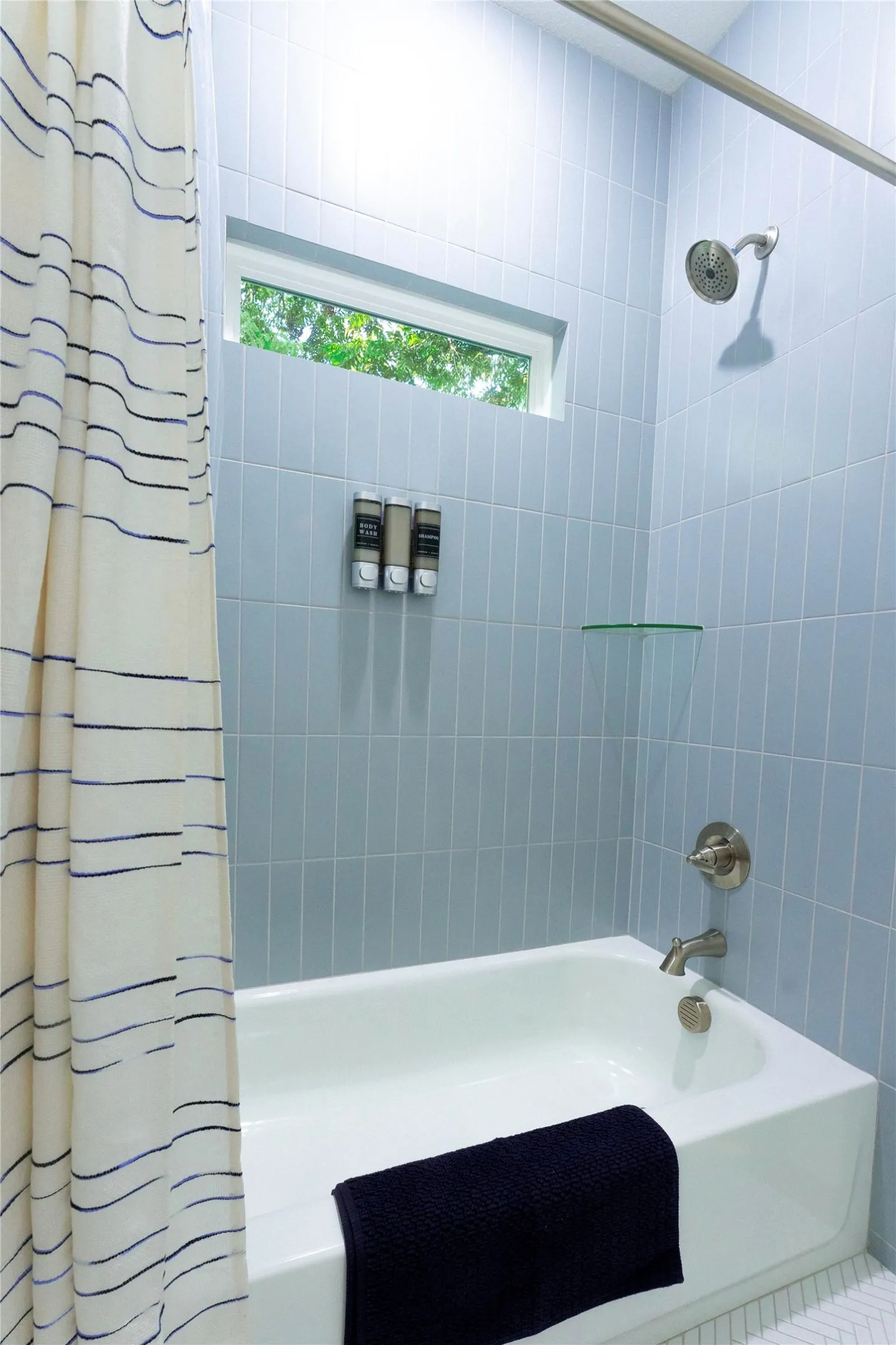 Contemporary bathroom featuring a tiled shower enclosure with glass panel, white subway tile walls, and brushed nickel showerhead