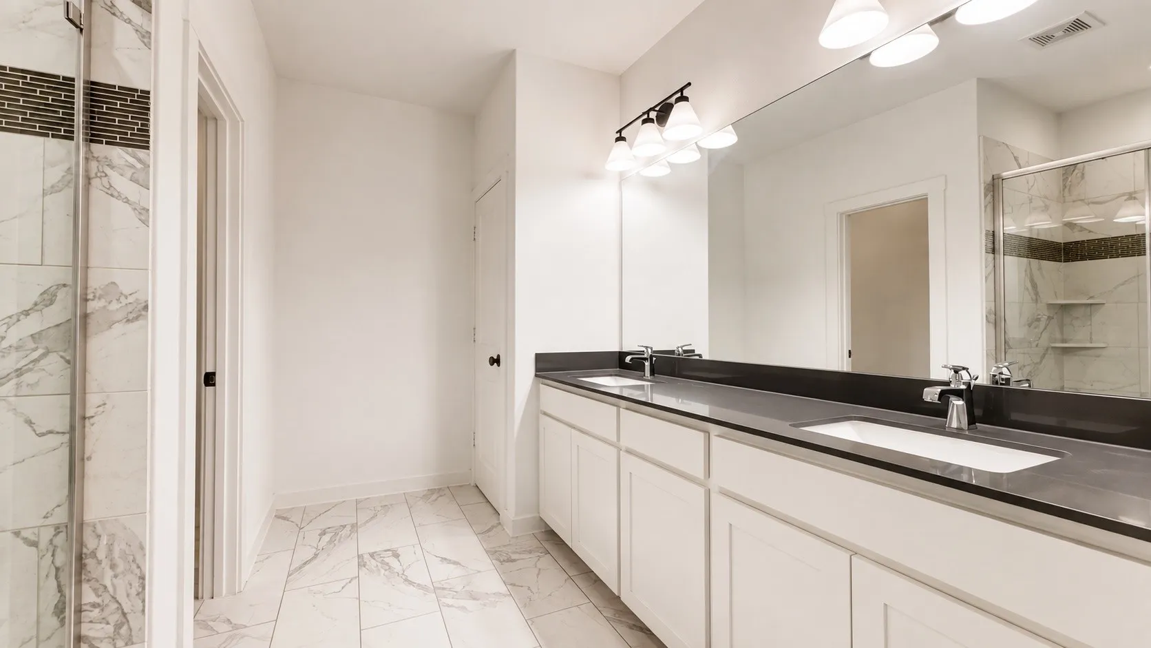 Double vanity with integrated sinks, dark countertop, and an expansive mirror