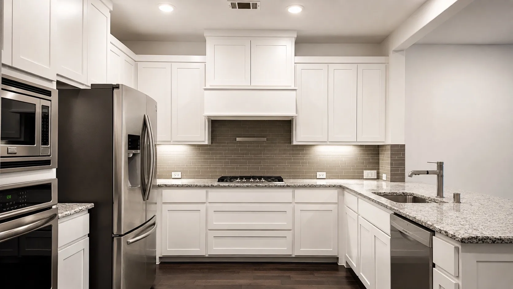 Kitchen featuring white shaker-style cabinetry, stainless steel appliances, granite countertops, a built-in microwave and oven combination, and a tile backsplash