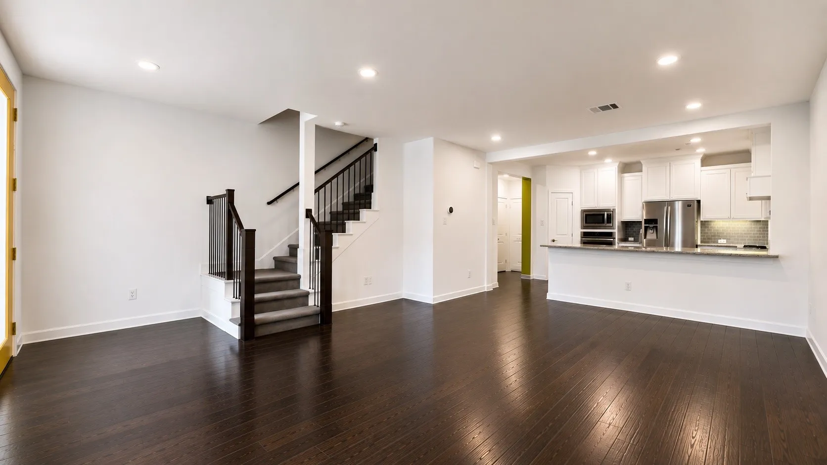 Open-concept living space featuring dark wood-finish flooring, white walls, and recessed lighting