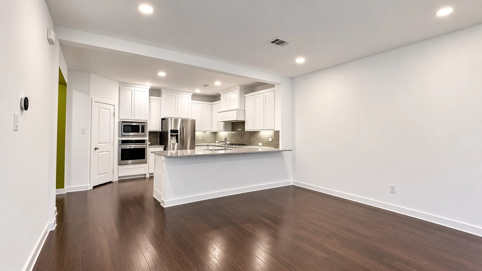 Open-concept living area with dark wood-finish flooring, recessed lighting, and a kitchen featuring white cabinetry, a large island with a stone countertop, stainless steel appliances, and a tiled backsplash
