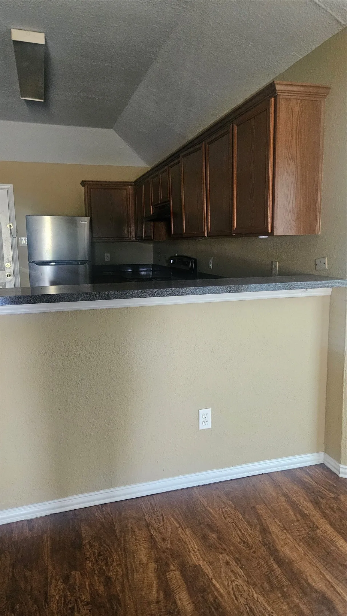 Wood-finish flooring, built-in cabinetry, and a stainless steel refrigerator