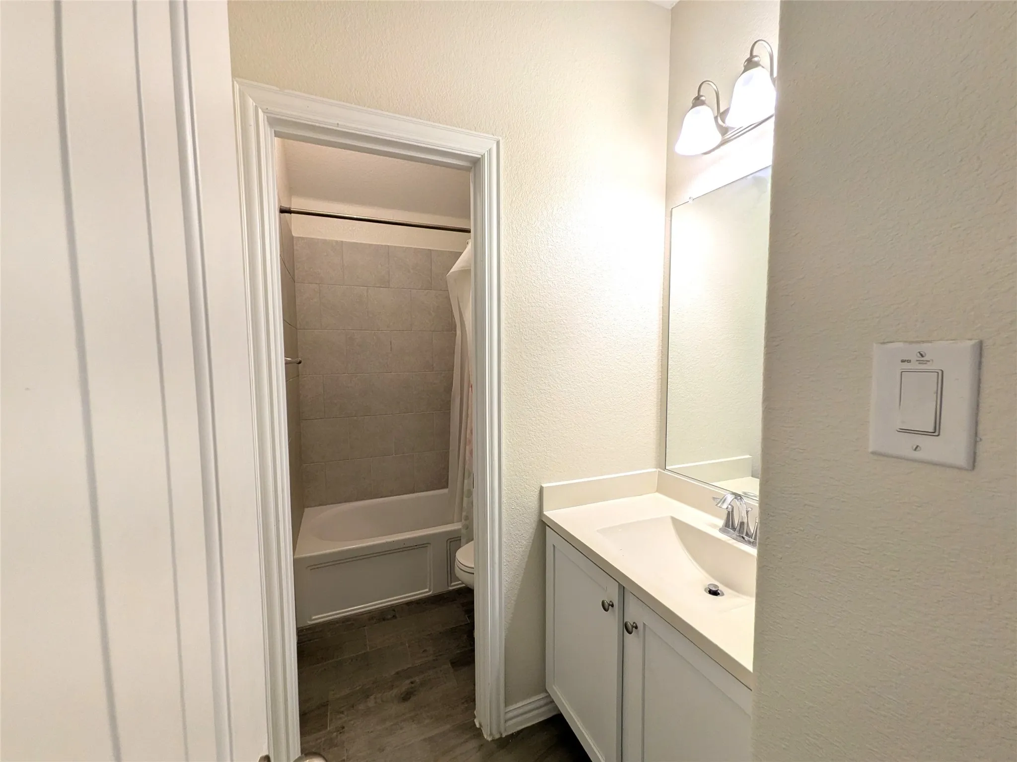 Bathroom featuring a white vanity with integrated sink, chrome faucet, and a large wall-mounted mirror